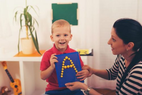 Little boy smiling during alphabet lesson with his speech therapist.