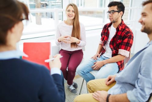 Group of young white people sitting in a therapy circle and sharing.