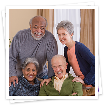 Older African American man and older white woman stand over their seated spouses. All are smiling.