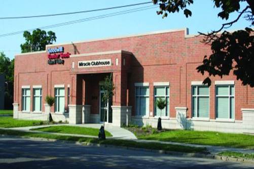 Street view of a brick building with the words Miracle Clubhouse over the doorway.